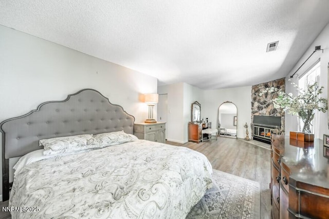 1419 Foster Dr, Reno, NV 89509 - bedroom featuring wood finished floors, a textured ceiling, arched walkways, and a stone fireplace