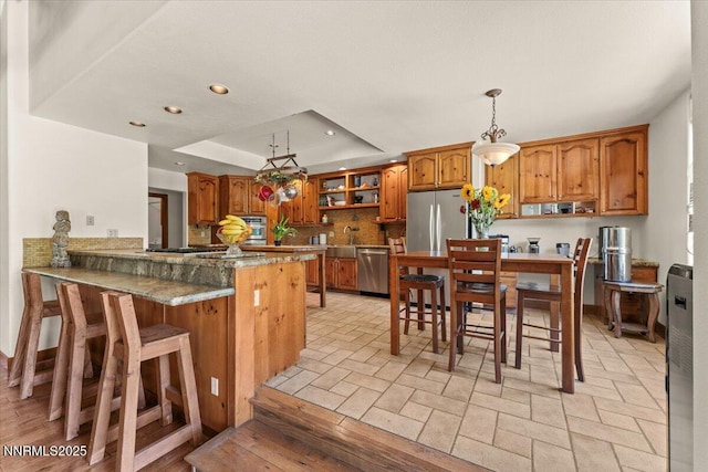 6195 Philoree Ln, Reno, NV 89511 - kitchen with appliances with stainless steel finishes, brown cabinets, a raised ceiling, a peninsula, and recessed lighting