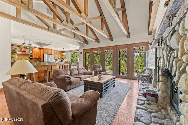 6195 Philoree Ln, Reno, NV 89511 - living room with a stone fireplace, high vaulted ceiling, light wood-style flooring, and beam ceiling