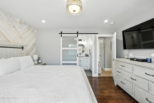 5863 Foggy Ct, Sun Valley, NV 89433 - bedroom featuring a barn door, dark wood-style flooring, recessed lighting, and connected bathroom