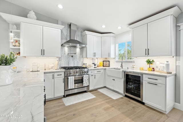 5863 Foggy Ct, Sun Valley, NV 89433 - kitchen featuring stainless steel stove, wall chimney range hood, beverage cooler, white cabinetry, and recessed lighting