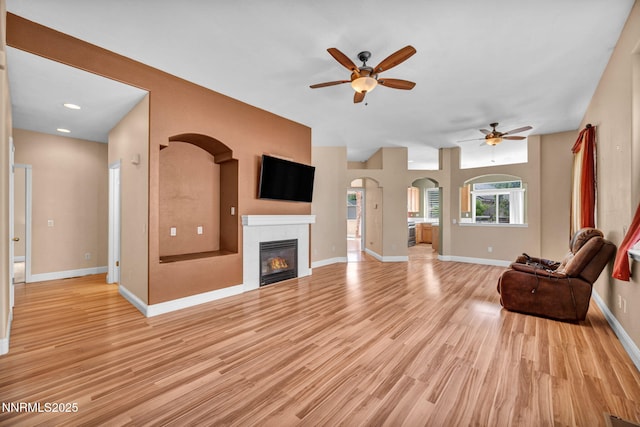 7449 Ambush Cir, Sparks, NV 89436 - unfurnished living room featuring a ceiling fan, arched walkways, a fireplace, light wood-style flooring, and recessed lighting