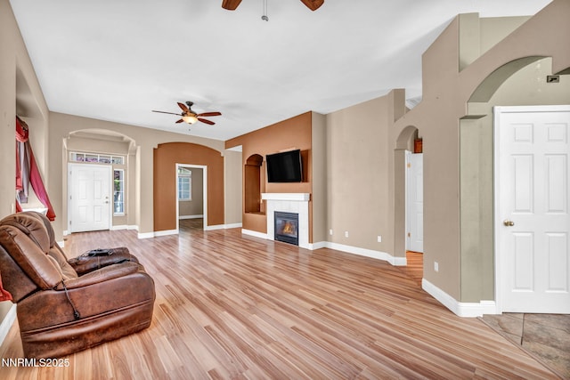 7449 Ambush Cir, Sparks, NV 89436 - living room with a ceiling fan, arched walkways, light wood-type flooring, and a tiled fireplace