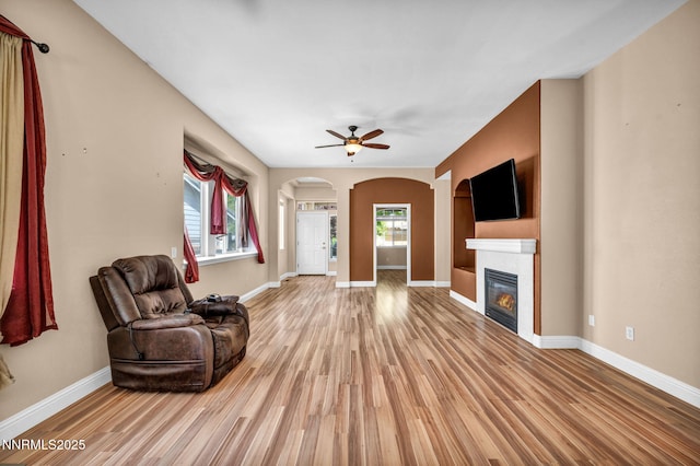 7449 Ambush Cir, Sparks, NV 89436 - living area featuring light wood-style floors, a glass covered fireplace, arched walkways, and ceiling fan