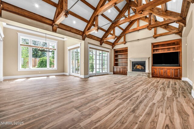 6145 Triple Crown Dr, Reno, NV 89511 - unfurnished living room featuring plenty of natural light, light wood finished floors, a glass covered fireplace, beam ceiling, and high vaulted ceiling