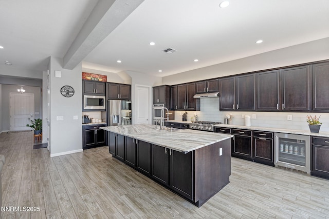 9435 Stony Hill Rd, Reno, NV 89521 - kitchen with beverage cooler, appliances with stainless steel finishes, under cabinet range hood, backsplash, and an island with sink