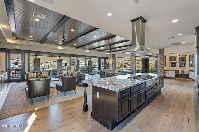 9435 Stony Hill Rd, Reno, NV 89521 - kitchen featuring stainless steel gas stovetop, open floor plan, island range hood, light wood finished floors, and a breakfast bar
