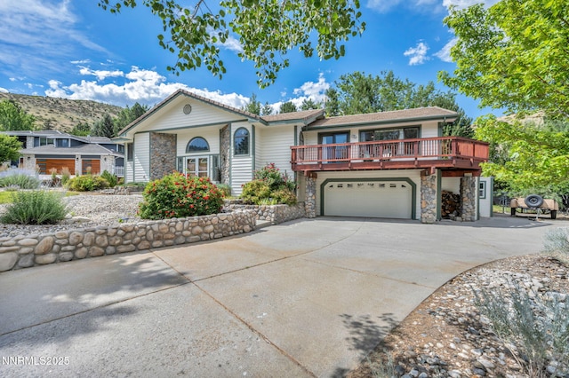 3279 Upland Ct, Carson City, NV 89703 - view of front of house featuring stone siding, a garage, driveway, and a wooden deck