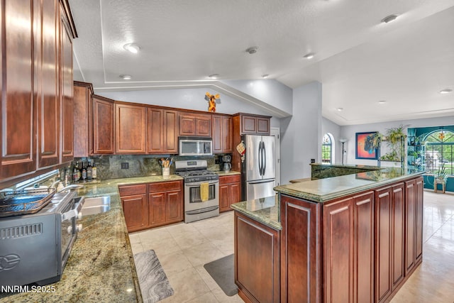 3279 Upland Ct, Carson City, NV 89703 - kitchen featuring stainless steel appliances, vaulted ceiling, tasteful backsplash, reddish brown cabinets, and stone counters
