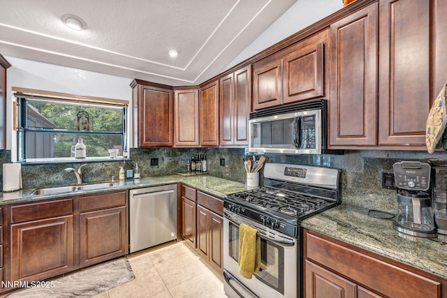 3279 Upland Ct, Carson City, NV 89703 - kitchen with stainless steel appliances, tasteful backsplash, light tile patterned floors, lofted ceiling, and dark stone counters