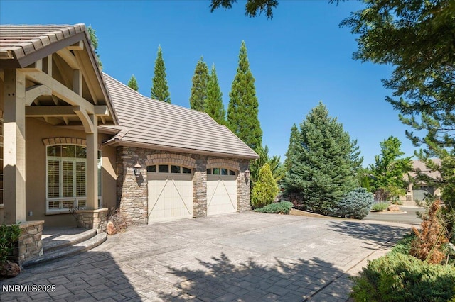 4990 Mountainshyre Rd, Reno, NV 89519 - view of property exterior with stone siding, a tile roof, stucco siding, an attached garage, and driveway
