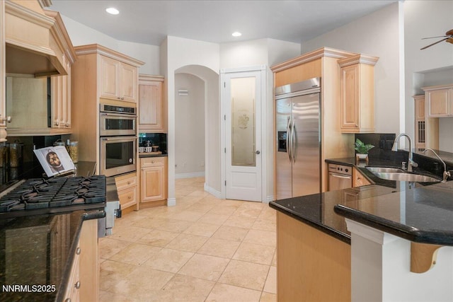 4990 Mountainshyre Rd, Reno, NV 89519 - kitchen with appliances with stainless steel finishes, light brown cabinetry, tasteful backsplash, ceiling fan, and arched walkways