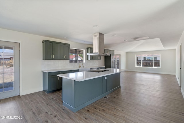 684 Carson River Dr, Fallon, NV 89406 - kitchen with island range hood, wood finished floors, decorative backsplash, light countertops, and recessed lighting