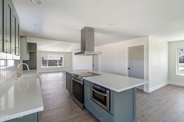 684 Carson River Dr, Fallon, NV 89406 - kitchen featuring island range hood, stainless steel appliances, light wood-style flooring, and light countertops