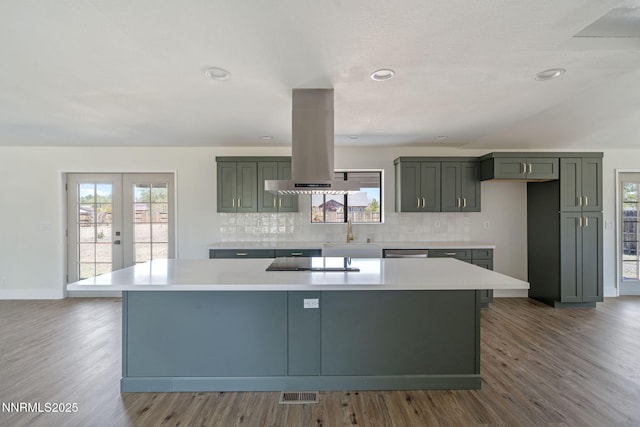 684 Carson River Dr, Fallon, NV 89406 - kitchen with island exhaust hood, a center island, decorative backsplash, black electric cooktop, and plenty of natural light