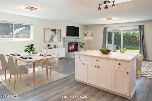 875 Camino Real Dr, Sparks, NV 89434 - kitchen featuring a brick fireplace, white cabinets, light wood-type flooring, light countertops, and a textured ceiling