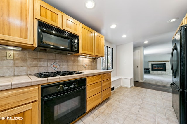 299 Chimney Rock Rd, Stateline, NV 89449 - kitchen with black appliances, tile counters, a glass covered fireplace, backsplash, and recessed lighting