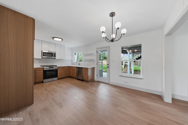 1305 Gault Way, Sparks, NV 89431 - kitchen with stainless steel appliances, light wood finished floors, light countertops, decorative backsplash, and a chandelier