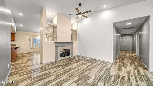 2015 Flycatcher Dr, Spanish Springs, NV 89441 - unfurnished living room featuring light wood-style floors, a ceiling fan, a premium fireplace, recessed lighting, and lofted ceiling
