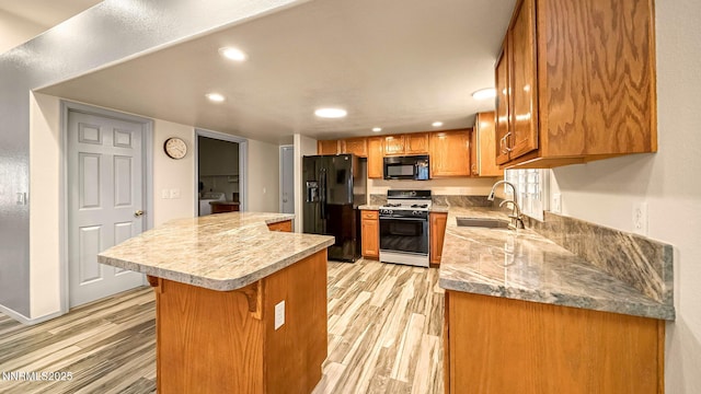 2015 Flycatcher Dr, Spanish Springs, NV 89441 - kitchen with black appliances, a kitchen island, light wood-type flooring, recessed lighting, and brown cabinets