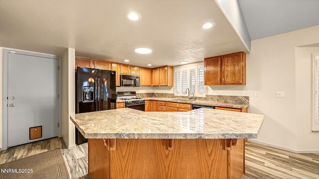 2015 Flycatcher Dr, Spanish Springs, NV 89441 - kitchen with black appliances, light countertops, recessed lighting, light wood-style flooring, and a kitchen bar