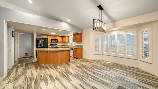 2015 Flycatcher Dr, Spanish Springs, NV 89441 - kitchen with black appliances, lofted ceiling, brown cabinetry, a kitchen breakfast bar, and light countertops