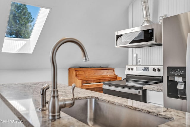 911 F St, Sparks, NV 89431 - kitchen featuring stainless steel appliances, white cabinetry, light stone countertops, and a skylight
