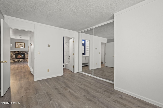 807 Alder Ave Unit 14, Incline Village, NV 89451 - unfurnished bedroom featuring wood finished floors, a stone fireplace, a textured ceiling, and connected bathroom