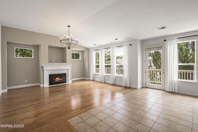 4833 Ramcreek Trl, Reno, NV 89519 - unfurnished living room featuring plenty of natural light, a fireplace with flush hearth, a chandelier, vaulted ceiling, and wood finished floors