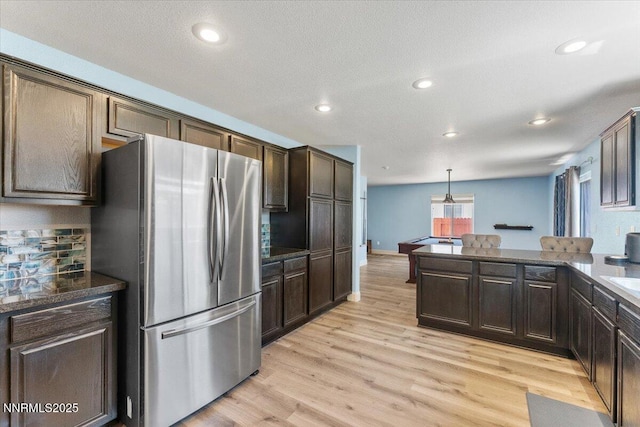 18324 Dustin Ct, Reno, NV 89508 - kitchen with freestanding refrigerator, dark brown cabinetry, light wood-type flooring, recessed lighting, and tasteful backsplash