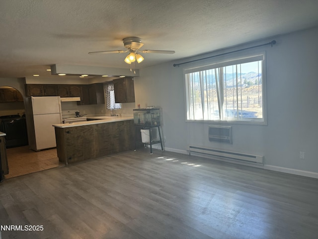 4440 Debra Ln, Winnemucca, NV 89445 - kitchen with white appliances, a baseboard radiator, a peninsula, wood finished floors, and light countertops