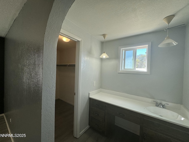 4440 Debra Ln, Winnemucca, NV 89445 - bathroom with a textured ceiling, vanity, wood finished floors, and a walk in closet