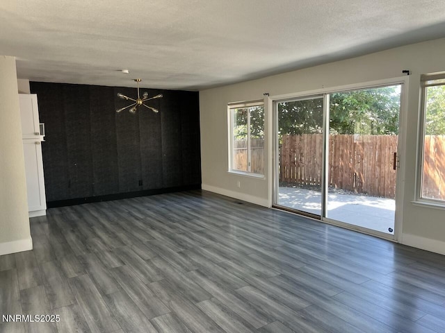 6845 Forsythia Way, Reno, NV 89506 - empty room featuring a chandelier, plenty of natural light, dark wood-type flooring, and a textured ceiling