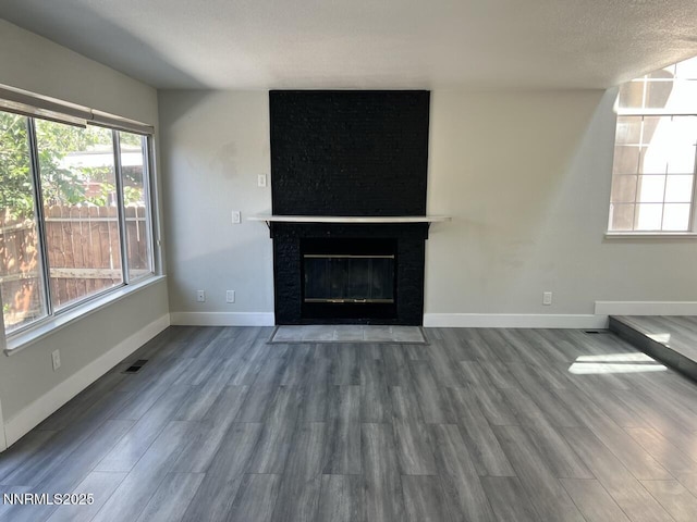6845 Forsythia Way, Reno, NV 89506 - unfurnished living room with wood finished floors, healthy amount of natural light, and a fireplace with flush hearth