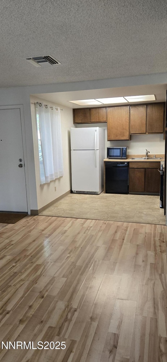 2111 Roundhouse Rd, Sparks, NV 89431 - kitchen featuring freestanding refrigerator, black dishwasher, light wood-style floors, a textured ceiling, and light countertops