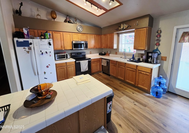 654 Keddie St, Fallon, NV 89406 - kitchen featuring stainless steel appliances, light wood-style floors, vaulted ceiling, and brown cabinetry