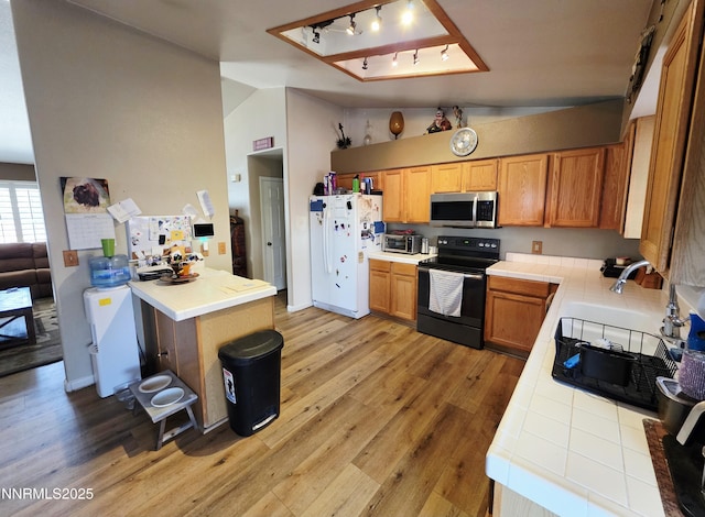 654 Keddie St, Fallon, NV 89406 - kitchen featuring black range with electric stovetop, freestanding refrigerator, stainless steel microwave, tile countertops, and light wood finished floors