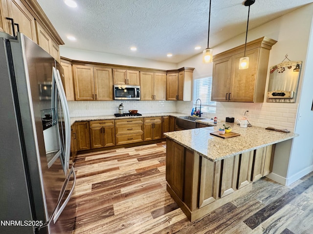 5290 Marla Dr, Winnemucca, NV 89445 - kitchen with appliances with stainless steel finishes, a peninsula, light wood-style flooring, a textured ceiling, and light stone countertops