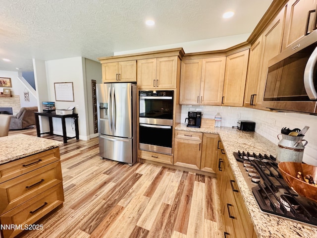 5290 Marla Dr, Winnemucca, NV 89445 - kitchen with stainless steel appliances, decorative backsplash, light wood-style floors, light stone counters, and open floor plan