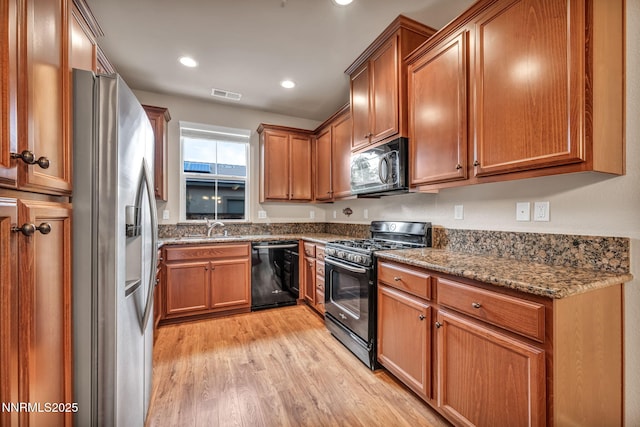6775 Russian Thistle Dr, Sparks, NV 89436 - kitchen with stainless steel appliances, light wood finished floors, brown cabinets, dark stone counters, and recessed lighting