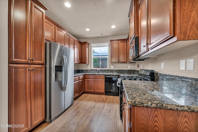 6775 Russian Thistle Dr, Sparks, NV 89436 - kitchen with black appliances, light wood-type flooring, brown cabinets, dark stone counters, and recessed lighting