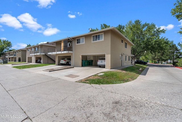 940 Jamaica Ave Unit 3, Reno, NV 89502 - rear view of house with an attached garage, stairs, concrete driveway, and stucco siding