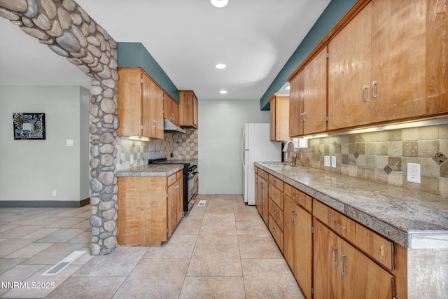 1320 Yori Ave, Reno, NV 89502 - kitchen with black stove, tasteful backsplash, under cabinet range hood, brown cabinets, and recessed lighting