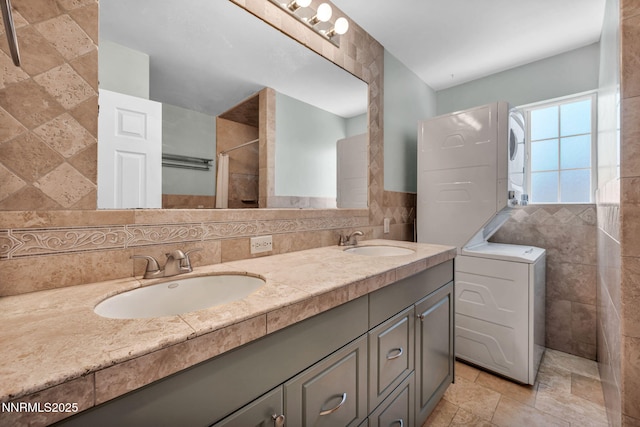 1320 Yori Ave, Reno, NV 89502 - full bathroom with stacked washing machine and dryer, tile walls, double vanity, a tile shower, and stone finish floors