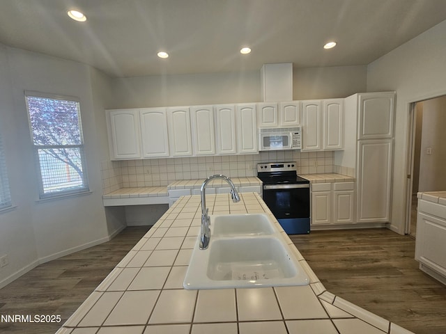 2735 Avenida De Landa, Reno, NV 89523 - kitchen with tile counters, stainless steel range with electric cooktop, white microwave, dark wood-type flooring, and white cabinetry
