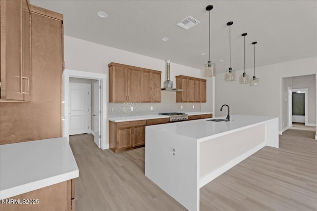 2800 Pamela Pl, Minden, NV 89423 - kitchen with brown cabinetry, light wood-type flooring, decorative backsplash, light countertops, and an island with sink