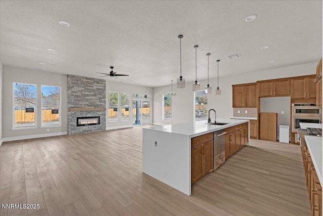 2800 Pamela Pl, Minden, NV 89423 - kitchen with stainless steel dishwasher, brown cabinets, ceiling fan, light wood finished floors, and a stone fireplace