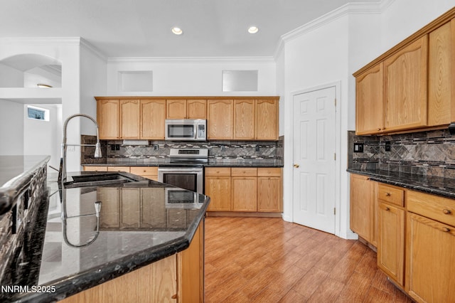 1048 Brierwood Ln, Fernley, NV 89408 - kitchen with stainless steel appliances, arched walkways, ornamental molding, decorative backsplash, and dark stone counters