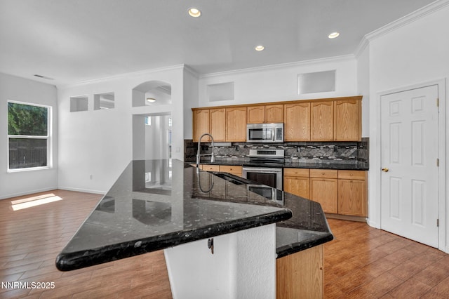 1048 Brierwood Ln, Fernley, NV 89408 - kitchen with stainless steel appliances, backsplash, light wood-style flooring, arched walkways, and crown molding