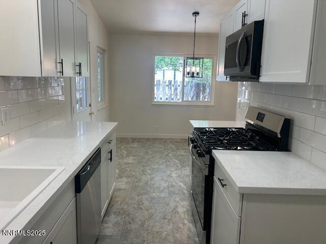 3220 Rice Rd, Fallon, NV 89406 - kitchen with appliances with stainless steel finishes, a chandelier, tasteful backsplash, light countertops, and decorative light fixtures